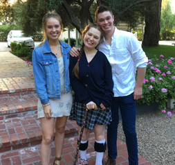 Taylor Carty standing outside arm in arm with siblings