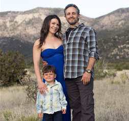 Miles Lessen with wife and young son outside in front of mountain scene