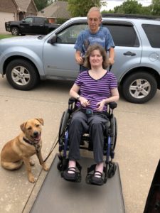 Leah Campbell and her service dog. Leah is being pushed up the ramp of an accessible van.